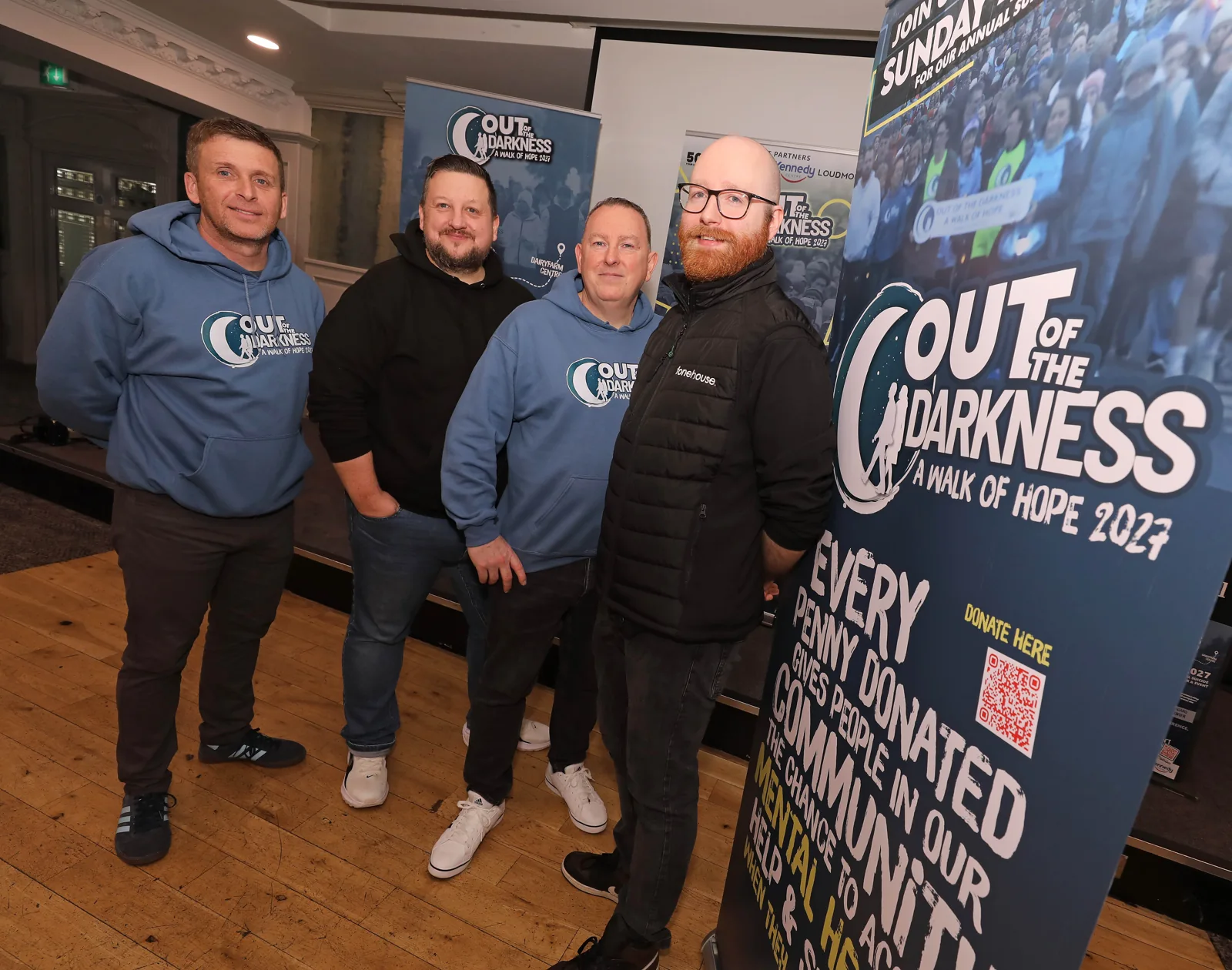 Three supporters beside the Out of the Darkness walk banners.