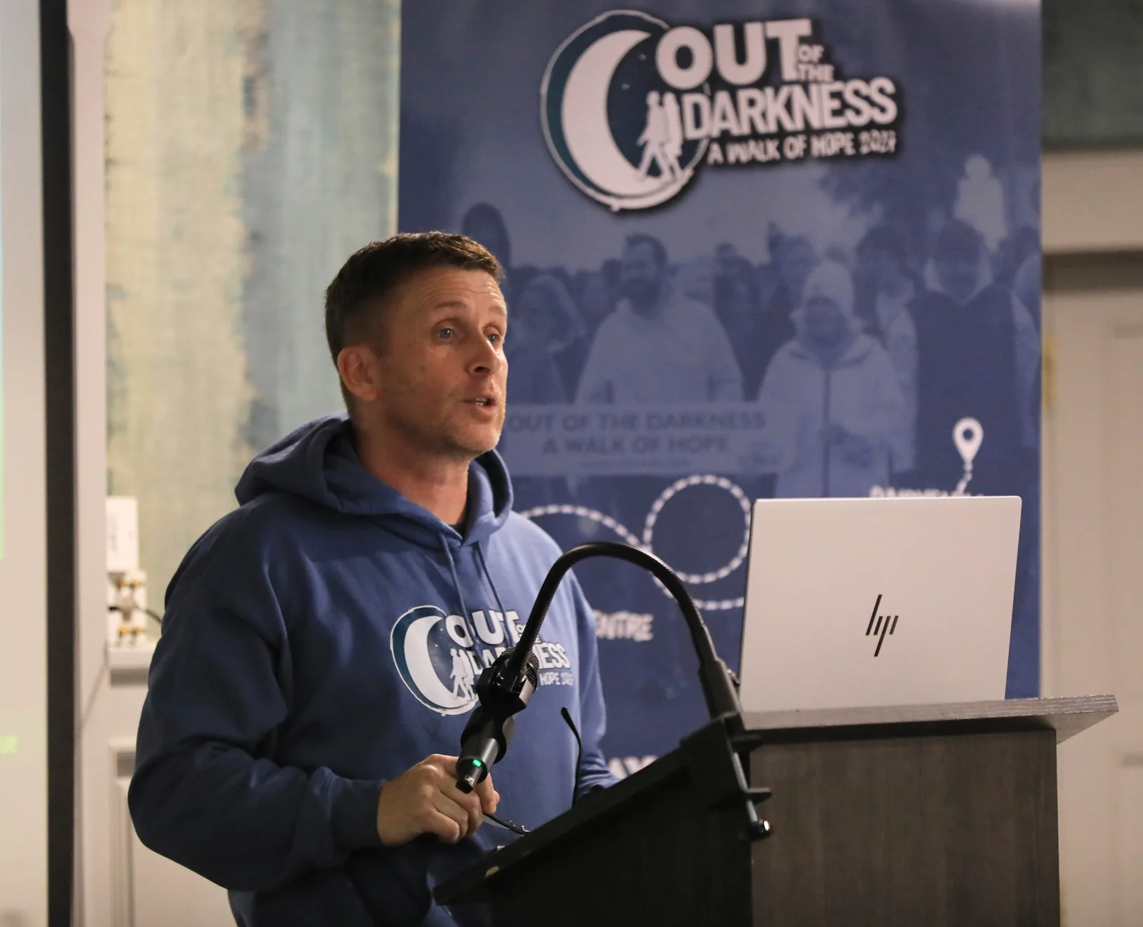 A speaker in an Out of the Darkness hoodie at the lectern.